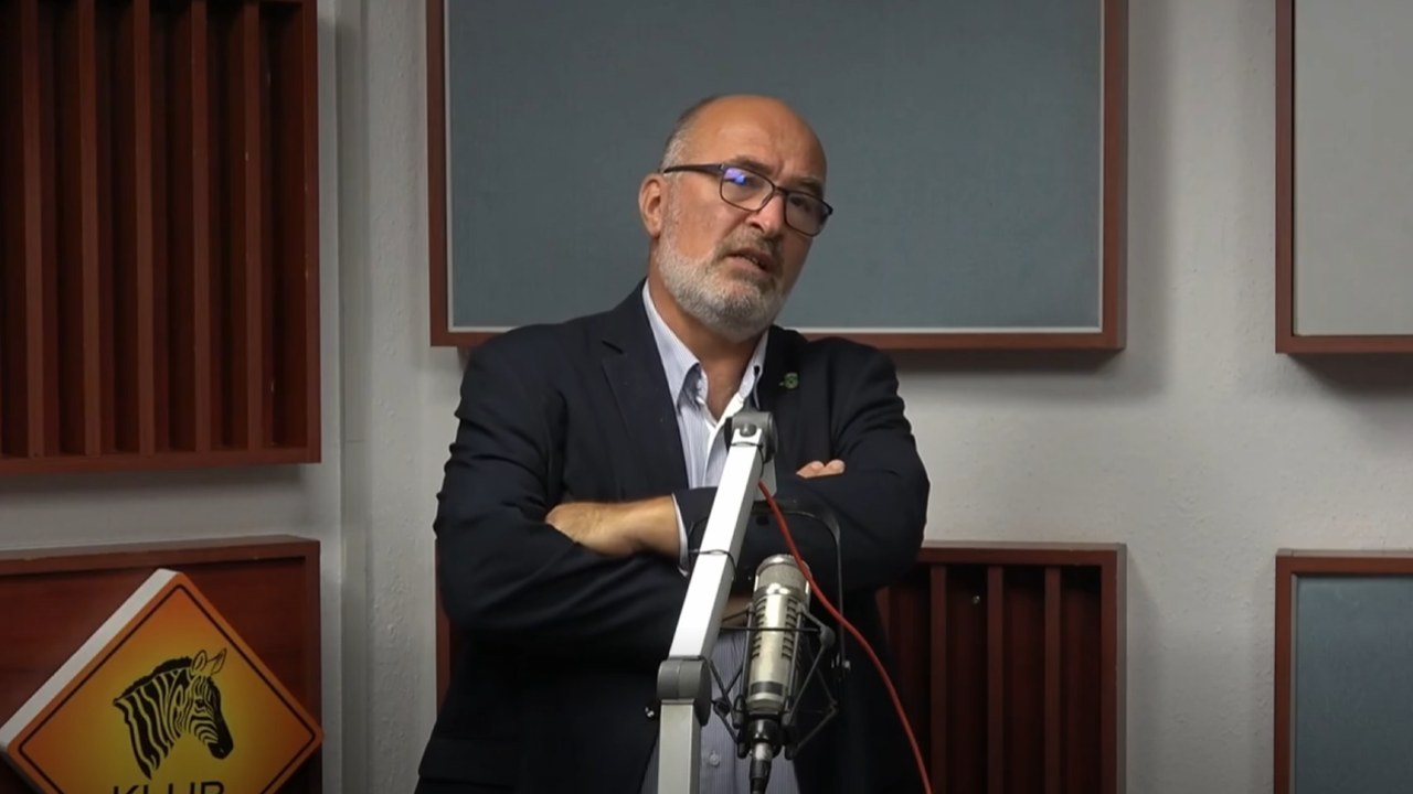 Pikó András, Józsefváros polgármestere összefont karral áll a mikrofon mögött a Klubrádió stúdiójában