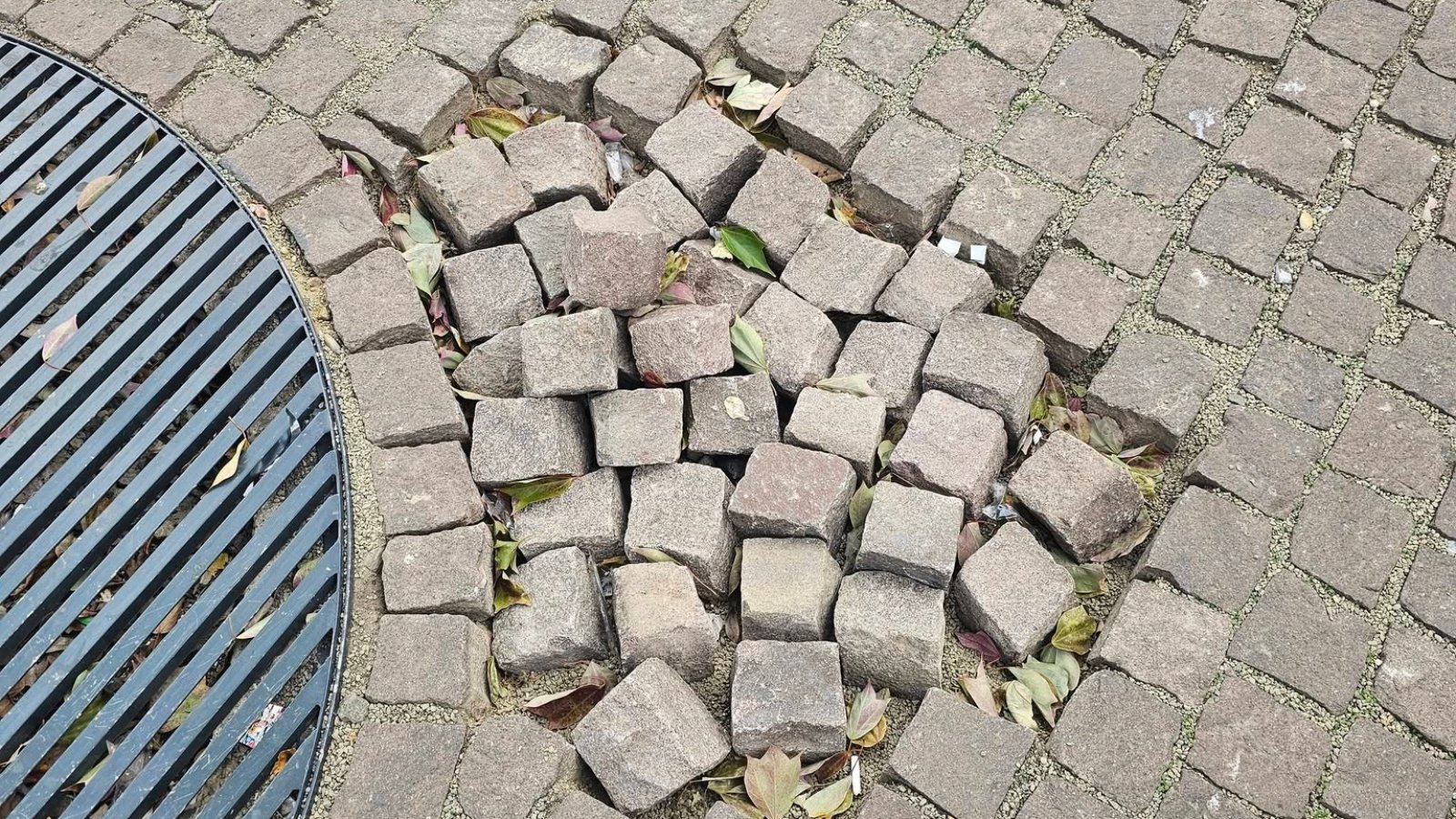 Kifordult, felszedett térkövek egy fa rácsa mellett a Blaha Lujza téren