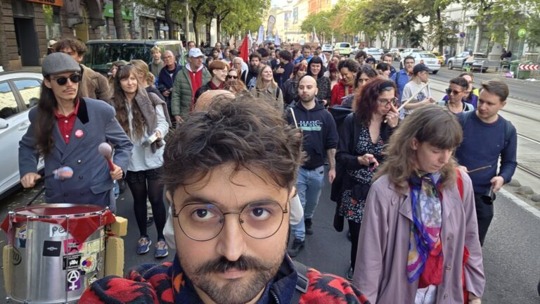 Shakkour Aram szelfije a Lakásmenet élén, mögötte dobosok és a felvonuló tömeg egy budapesti utcán